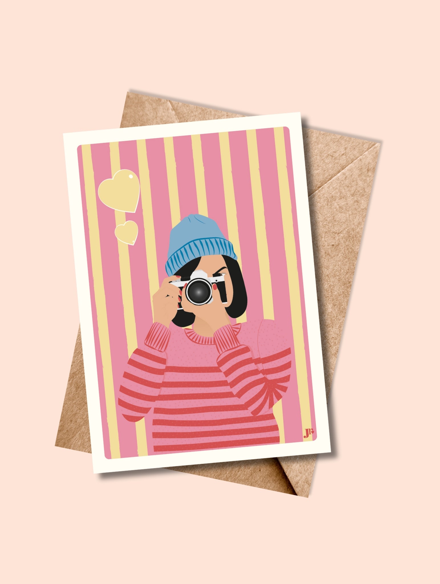 Carte postale Clic de Cœur avec enveloppe kraft, illustration pop d’une photographe en bonnet bleu et fond rose rayé.