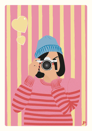 Illustration seule de la carte postale Clic de Cœur, jeune femme en pull rayé prenant une photo sur fond rose et jaune.
