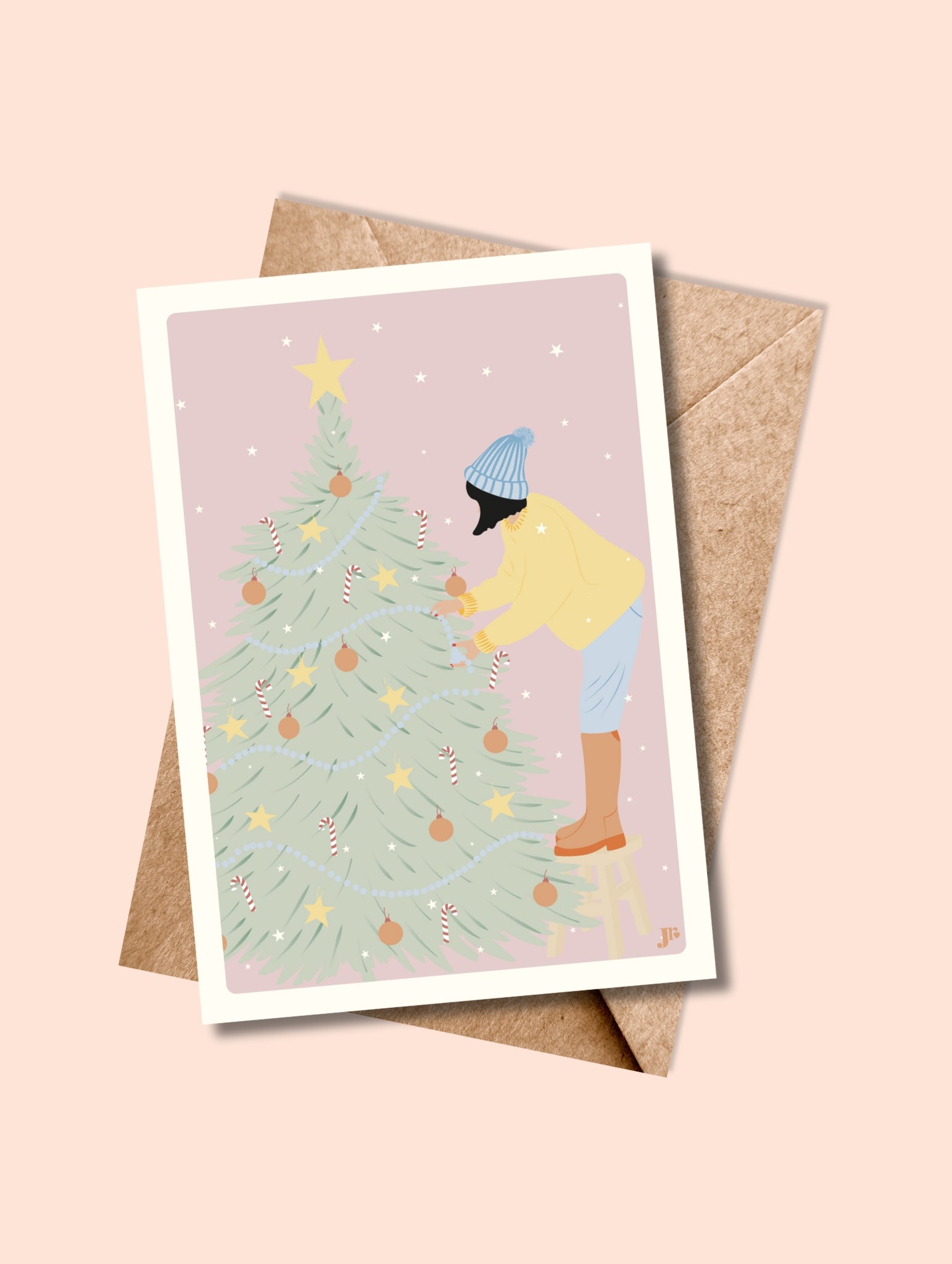 Carte postale Un Noël à la hauteur de rêve avec enveloppe kraft, illustration douce d’une femme décorant un grand sapin.